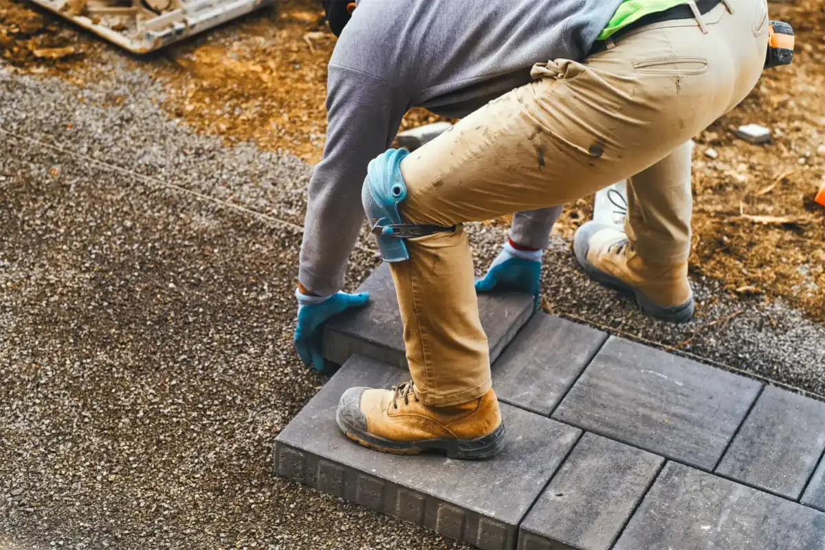 Contractor laying paver stones on a job site